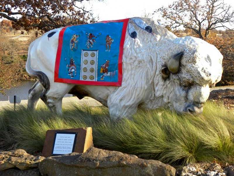 White painted buffalo sculpture with painted blanket representing entrance to Woolaroc museum.