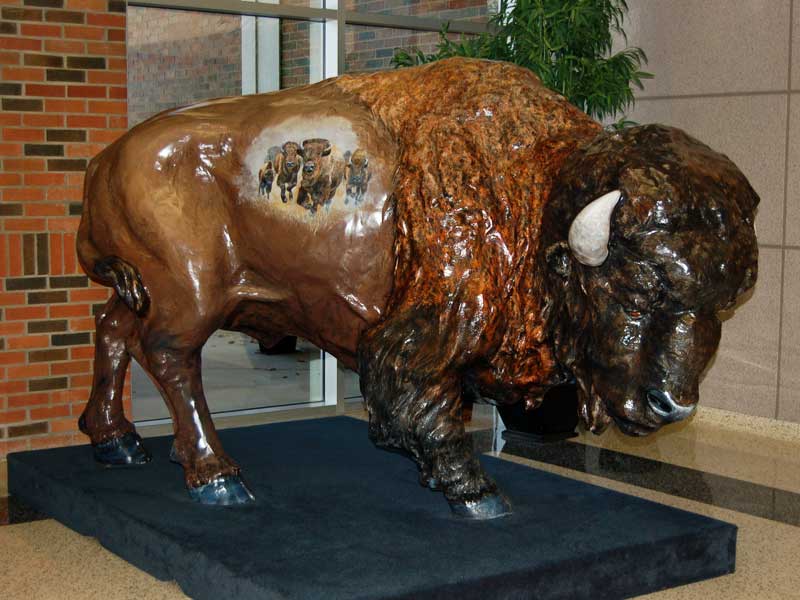Painted buffalo sculpture with scene of stampeding buffalo